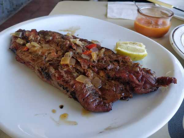 Local grilled meat served with red mojo in Guachinche Los Gómez, Tenerife.
